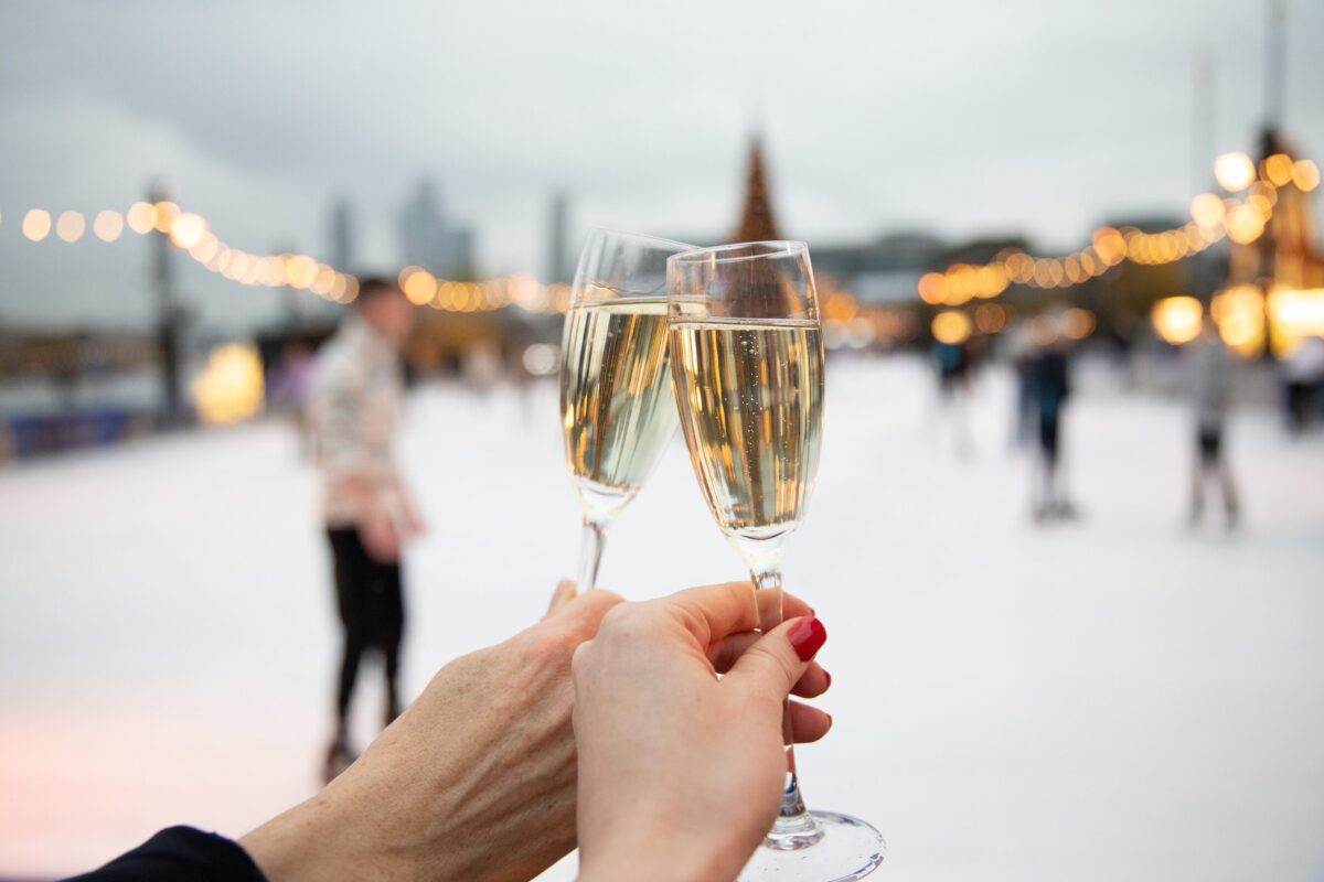 Two people holding a glass of sparkling wine on an ice rink
